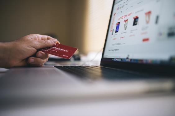 Laptop Computer With Turned-on Screen Beside Person Holding Red Smart Card