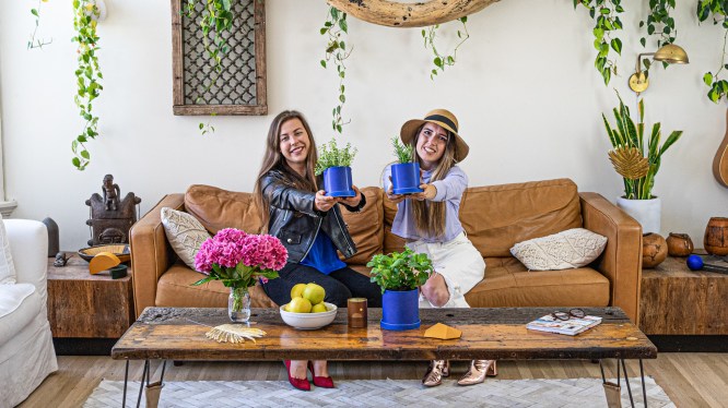 Two co-founders of Neverland sit on couch holding a plant