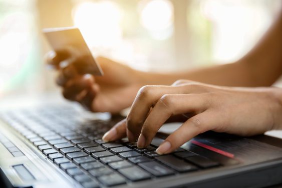 Image of hands holding credit card and using laptop to represent online shopping/e-commerce.