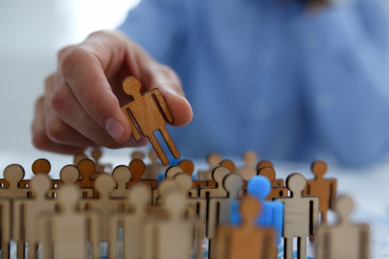 image of a businessman in a blue shirt picking up an individual figure from a crowd of others to represent poaching talent.