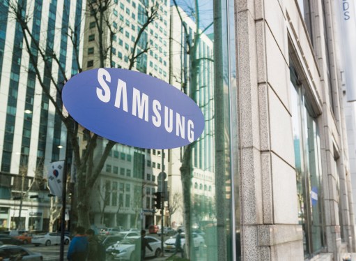 The Samsung logo on the window of one of the South Korean company's offices in Gangnam, central Seoul, with cars and people on the street reflected in the window.