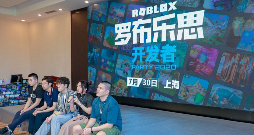 people seated in front of large Roblox screen