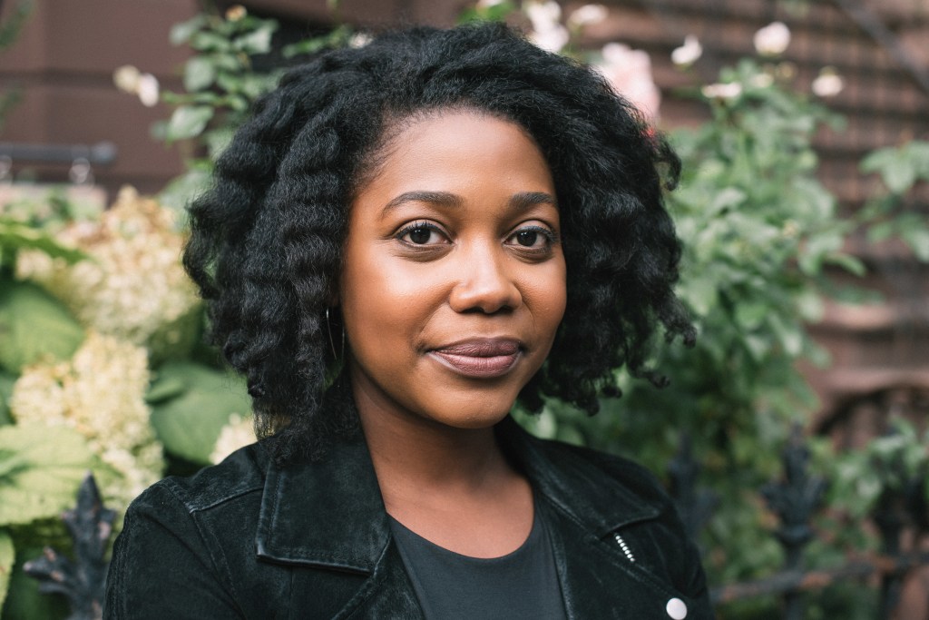 A black woman smiles to the camera