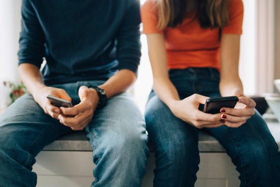 couple sitting, texting on smartphones