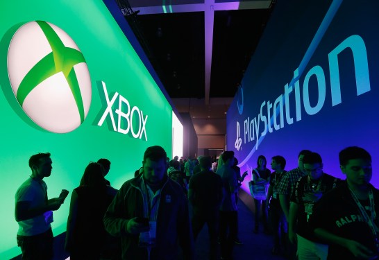 Xbox and PlayStation logos in dark convention hall