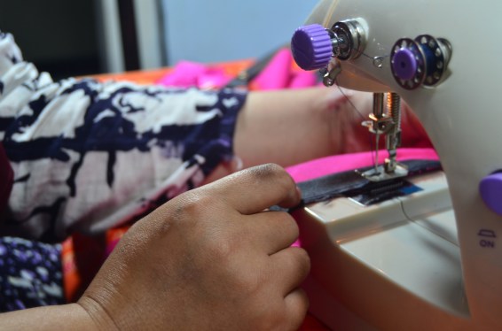 Sewist at sewing machine making a pink dress, used in post about Praktis