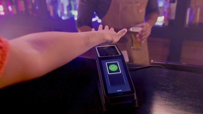 Person holding palm over an Amazon One device.