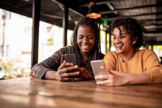 Photo of two friends sending money to each other through a digital wallet on their smartphones