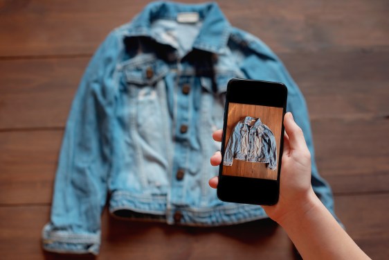 Woman comparing a denim shirt to a photo of it on smartphone