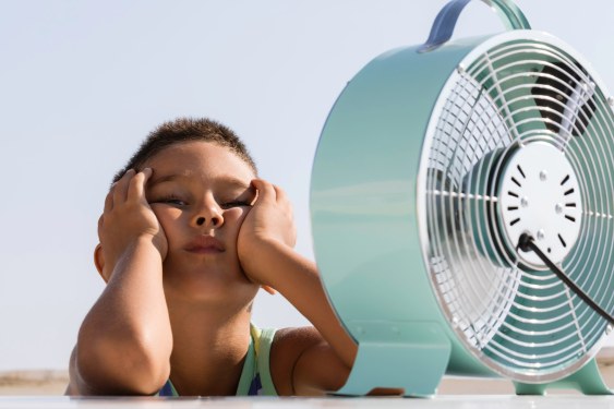 A child cools off in front of a fan.