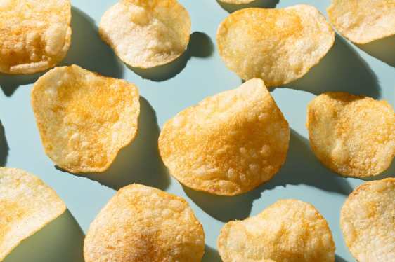 Potato chips sit against a light blue table.