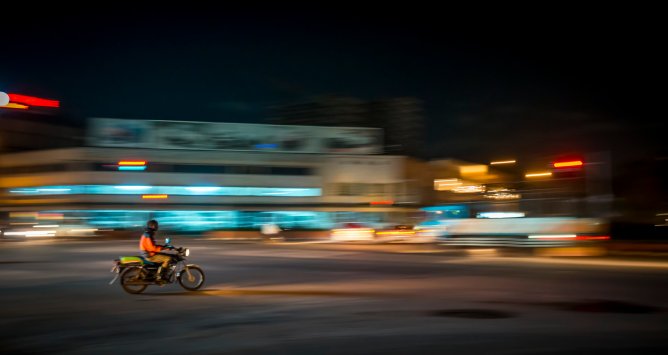 Man riding a motorbike in Kampala, Uganda, at night.