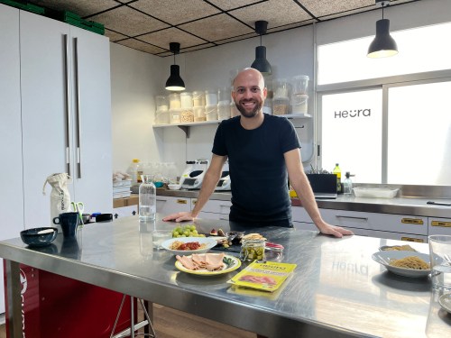 Heura CEO and founder Marc Coloma pictured in the company's demo kitchen with a spread of some of its products