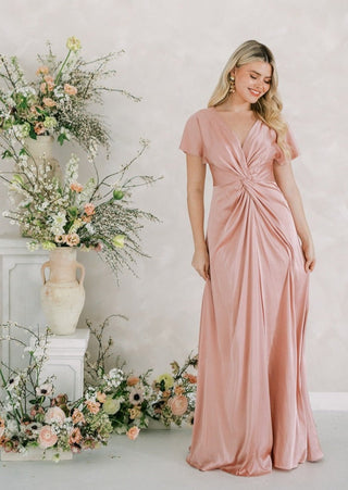 Blush pink satin maxi bridesmaid dress with flattering twist knot front detail and sleeves.