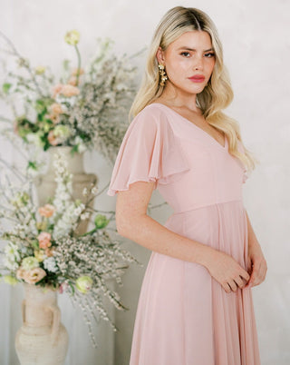 Blush pink chiffon maxi bridesmaid dress with flutter sleeves.