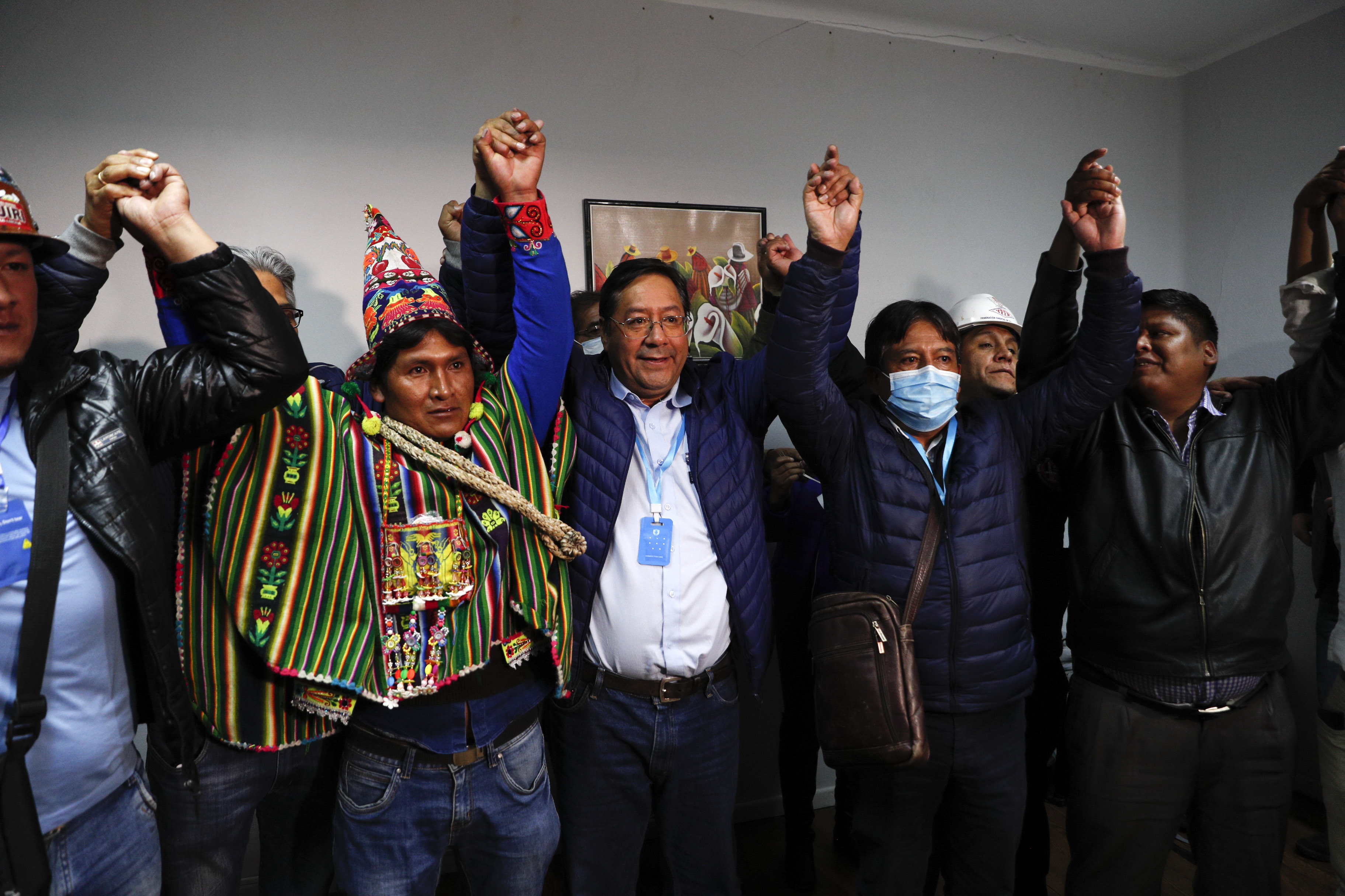 Luis Arce, center, Bolivian presidential candidate for the Movement Towards Socialism Party, MAS, and running mate David Choquehuanca, second right, celebrate during a press conference where they claim victory after general elections in La Paz, Bolivia, Monday, Oct. 19, 2020. (AP Photo/Juan Karita)