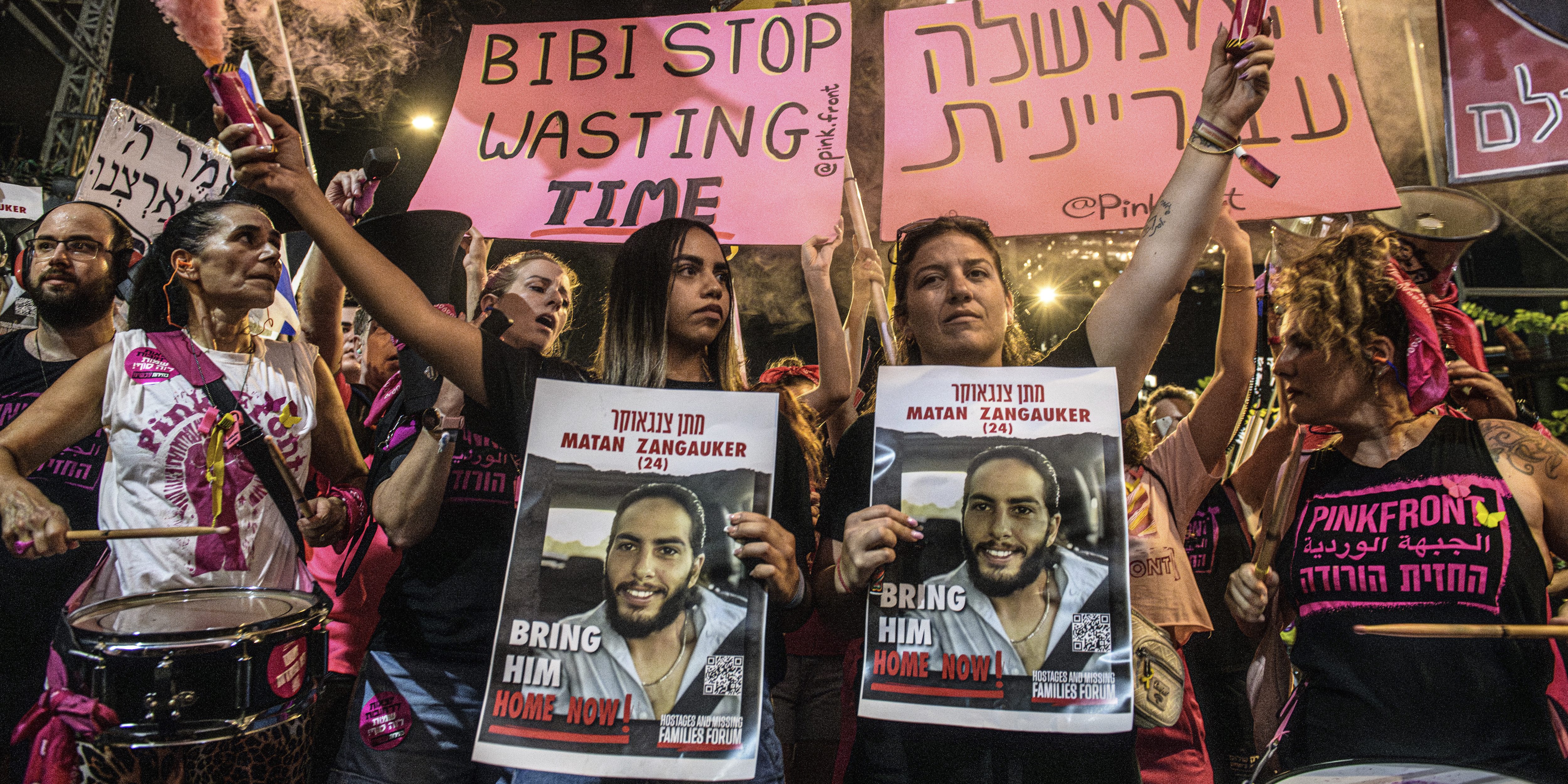 Natali Zangauker, sister of Israeli hostage Matan Zangauker, and her cousin holds a sign with Matan's photo while holding a pink smoke grenade under a sign that reads: "Bibi stop wasting Time". Thousands of Israelis demonstrated with the hostage's families against Prime Minister Benjamin Netanyahu, demanding an immediate hostage deal and ceasefire - as Israel awaits for the Iranian and Hezbollah attack. Tel Aviv, Israel. August 10th 2024. (Matan Golan / Sipa USA).(Sipa via AP Images)