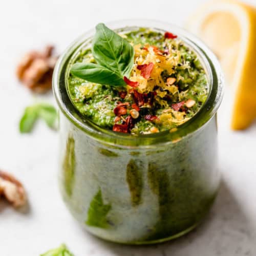 Basil walnut pesto in a small jar topped with lemon zest and red pepper flakes