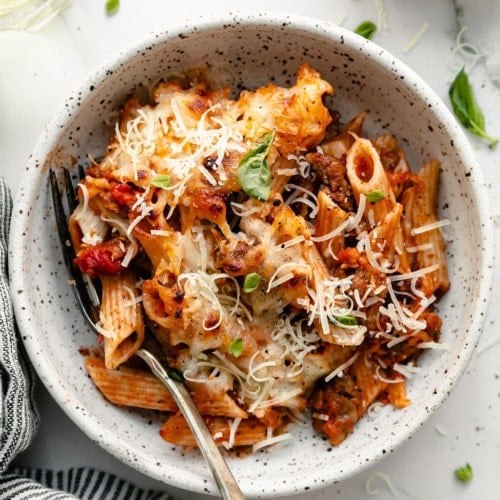 Overhead view baked ziti with Parmesan cheese on top served in stone bowl