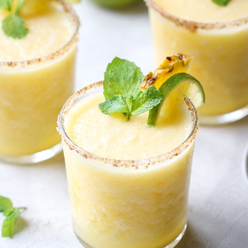 Short glasses filled with frozen pineapple margarita