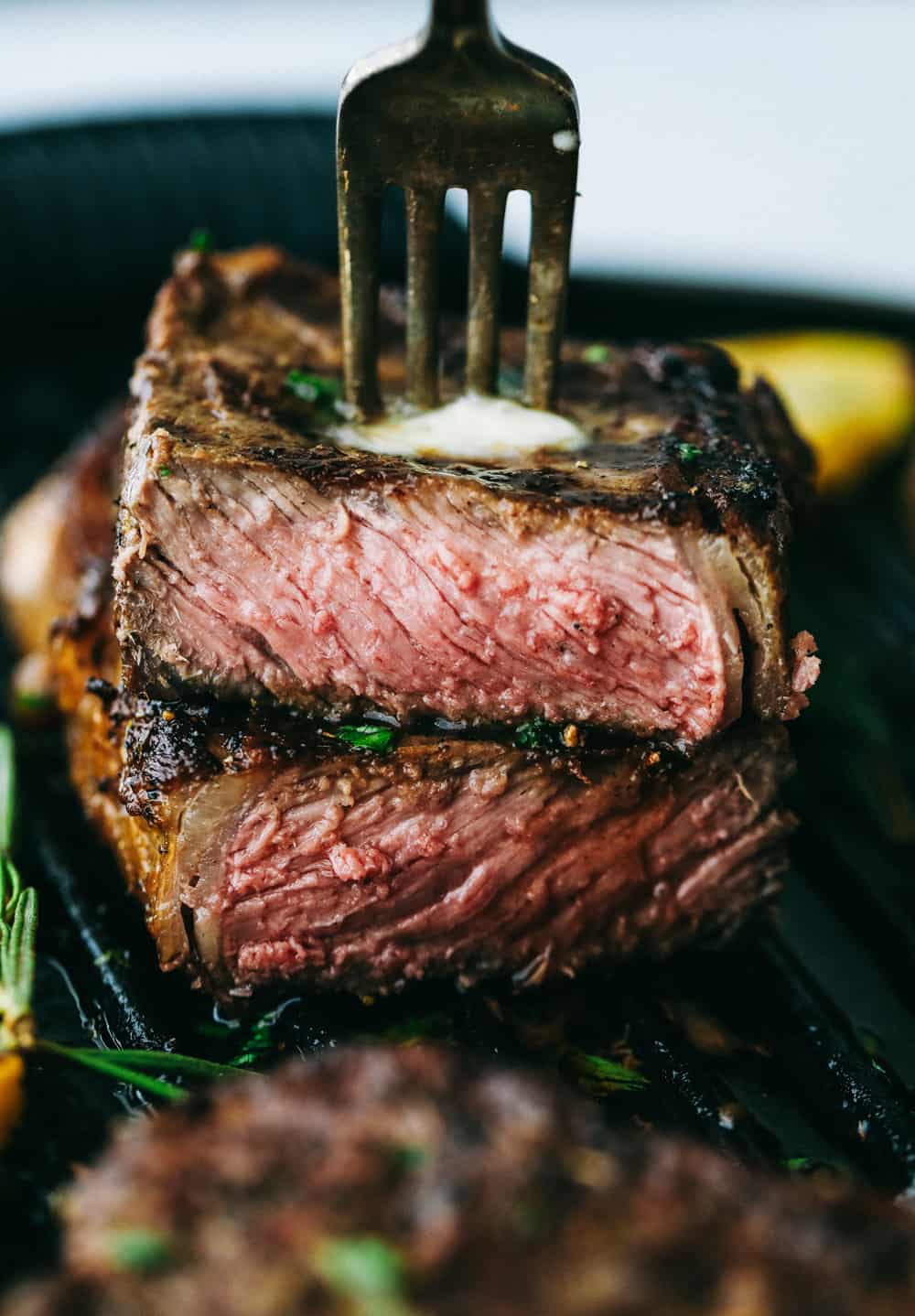 Taking a bite of steak with a fork.