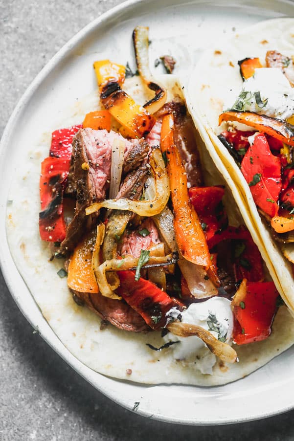 Steak fajitas in a tortilla on a white plate. 