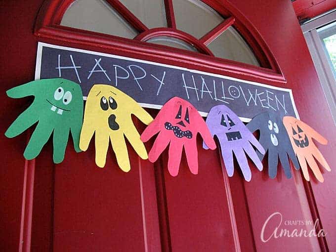 Happy Halloween hand banner craft - different color hands cut out and made into monsters and ghosts on the bottom of a sign.