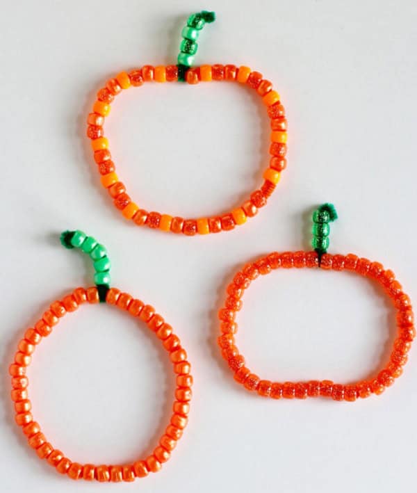 Pumpkins made by stringing orange beads beads on a pipe cleaner with green beads to make the stem.