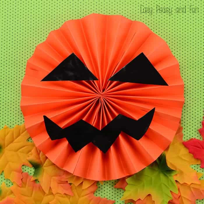 Orange paper folded into fans and attached to make a circle with black construction paper eyes and smile.