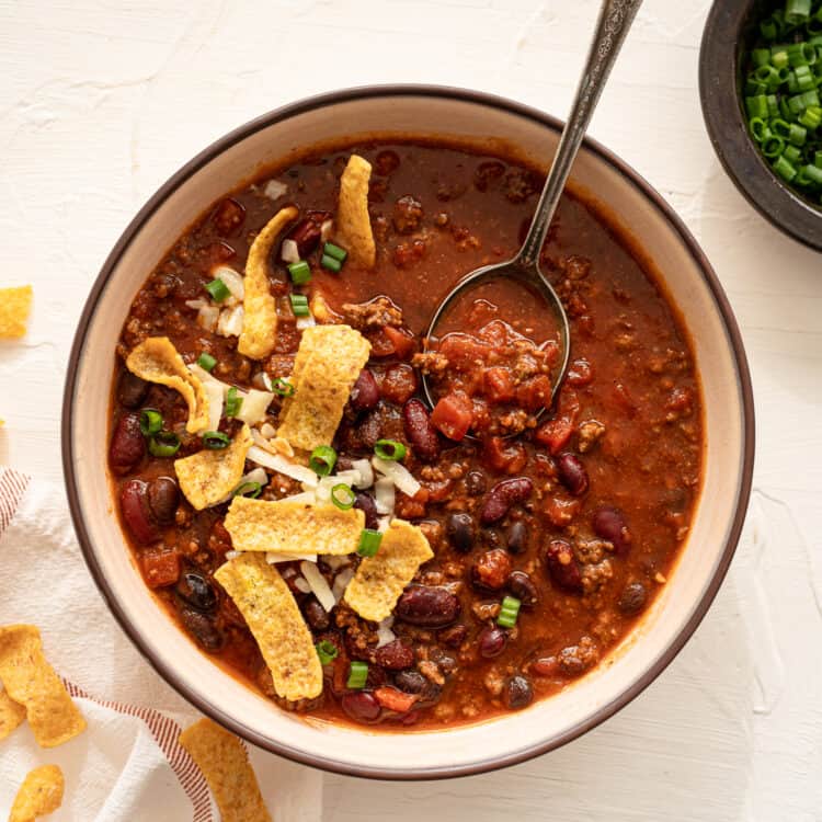 Stovetop Chili with a spoon topped with fritos chips.