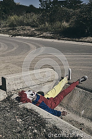 Scary clown lying down outdoors Stock Photo