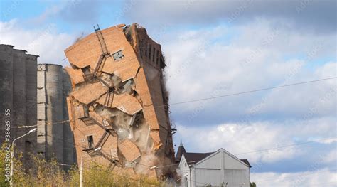 Industrial controlled explosion abandoned building on blue sky with white clouds background ...