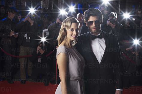 Serious Celebrity Couple On Red Carpet With Paparazzi In Background