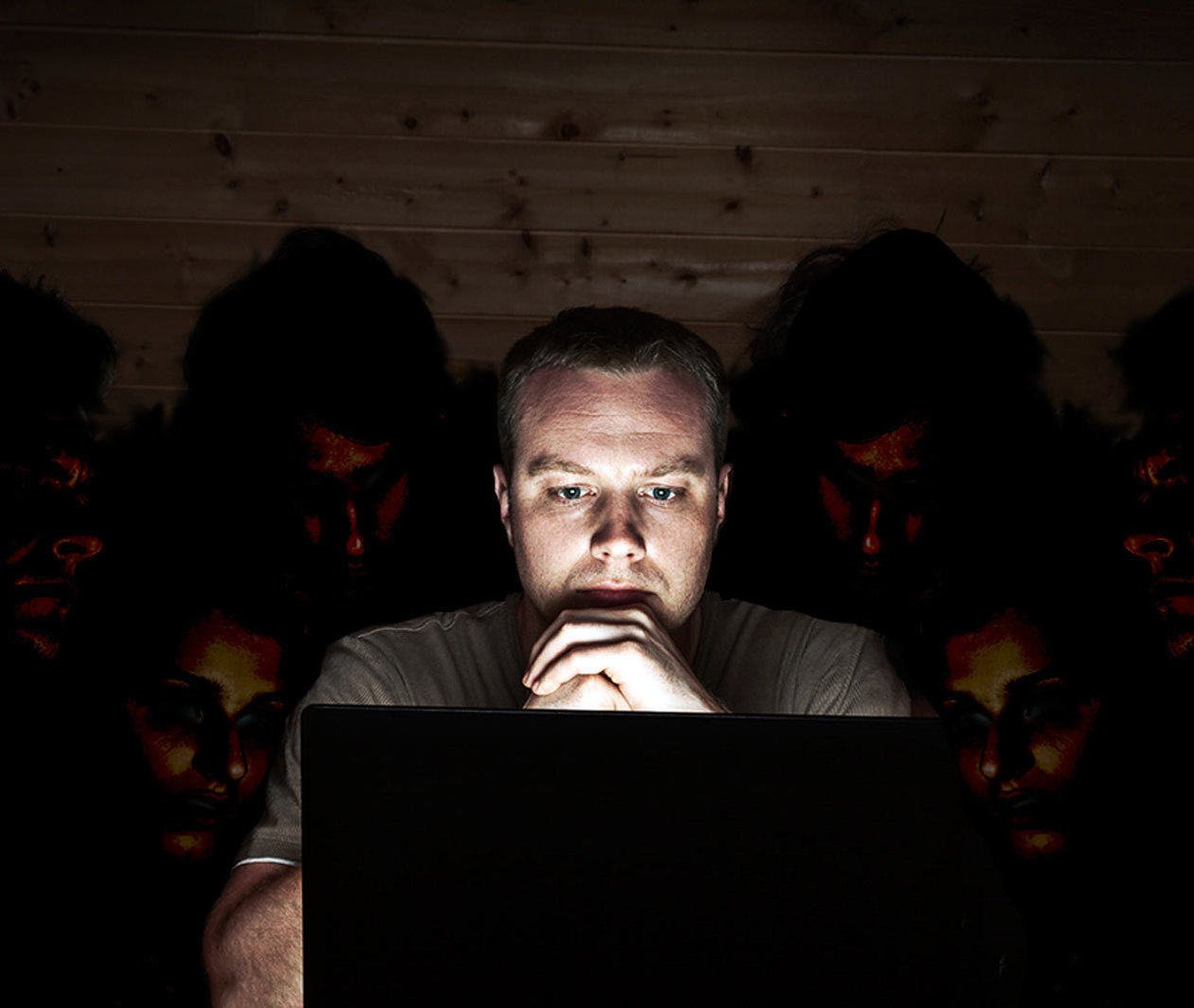 A cyber security threat – a man looks at his laptop, while people snoop over his shoulder.