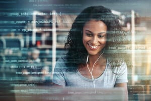 A mid-shot of a woman using a laptop superimposed over multiple lines of computer code