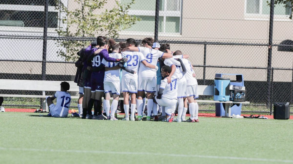 The UMass Boston's men's soccer team during a huddle. Photo by Salt Lake Photo Company via Beacon Athletics. 