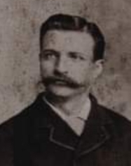 Black and white portrait of a mustachioed man. Appears to be in his mid-20s.