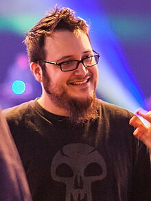 A smiling, bearded, bespectacled Edmund McMillen