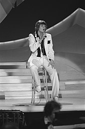 Fotografia em preto e branco de Johnny Logan se apresentando no palco no concurso de 1980