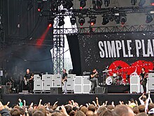 Several man performing onstage playing and singing into a microphone