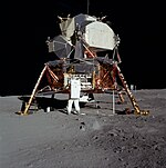 Un homme en combinaison spatiale sur la Lune, à côté d'un vaisseau spatial.