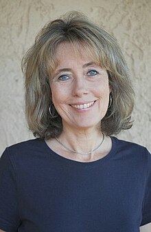 Charlotte Link wearing a dark blue t-shirt, smiling directly at camera