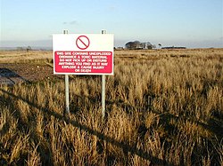 A sign in an upland field warning of dangerous items, toxic material and explosives