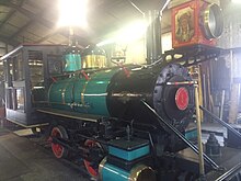 A steam locomotive in storage inside a roundhouse building.