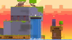 Gomez stands atop an anthropomorphic, purple structure with water falling from its orifices, as if it were crying. Trees grow atop the structure, grass lines the platforms, and the background is a deep yellow to orange gradient of a sunset. A bomb sits alone on the left side of the screen.