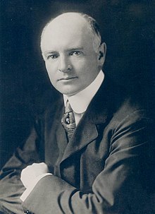 Black and white photograph of a middle-aged man in a dark suit and white shirt