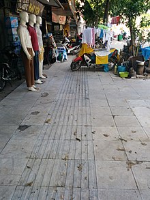 Photo of a sidewalk where a rectangle of concrete is filled with long, thin rectangular tiles instead of square ones