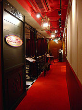 A view through a doorway into a cafe area; a sign reads Sakura Cafe and the interior is decorated using wood panelling with red and gold elements.