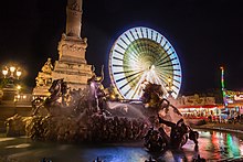 Photographie de la place des quinconces illuminée, avec une grande roue.