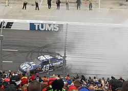 Jimmie Johnson executing a burnout on a flat surface after winning a race